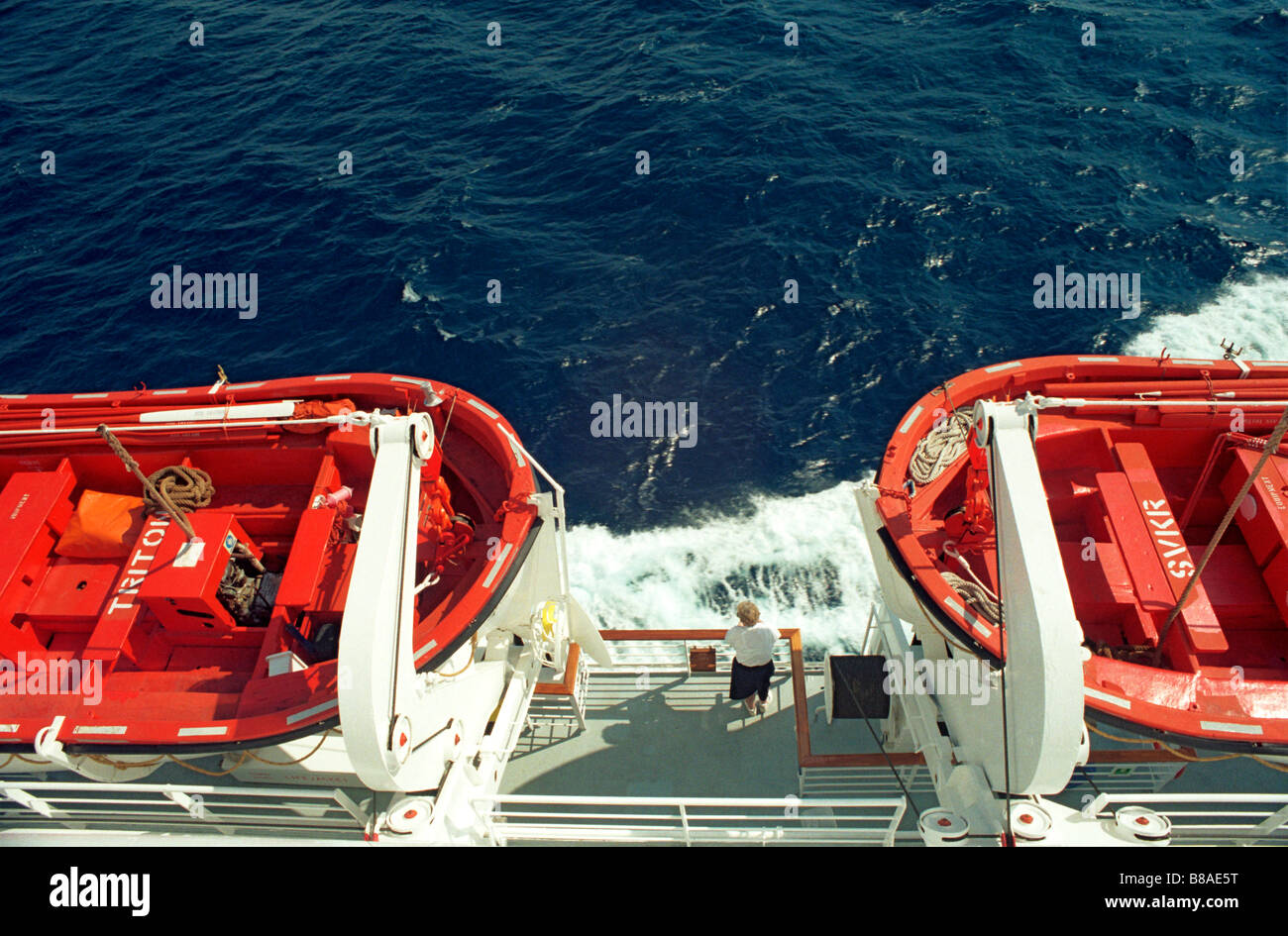 Eine Frau, Blick auf das Meer zwischen zwei Rettungsboote an Bord eines Kreuzfahrtschiffes in der mediterranen Stockfoto