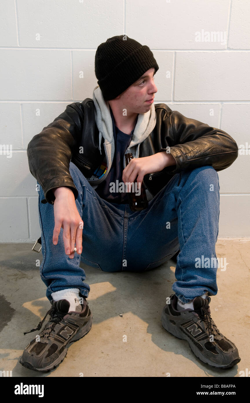 Teenager Junge sitzt mit dem Rücken gegen die Wand, trinken und Rauchen Stockfoto