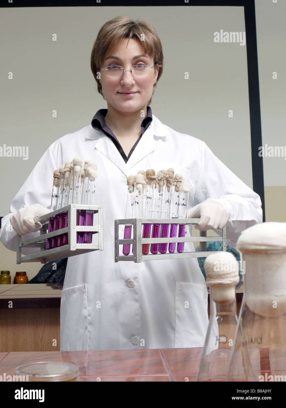 Porträt von weiblichen Labortechniker holding Racks mit Reagenzgläsern Stockfoto
