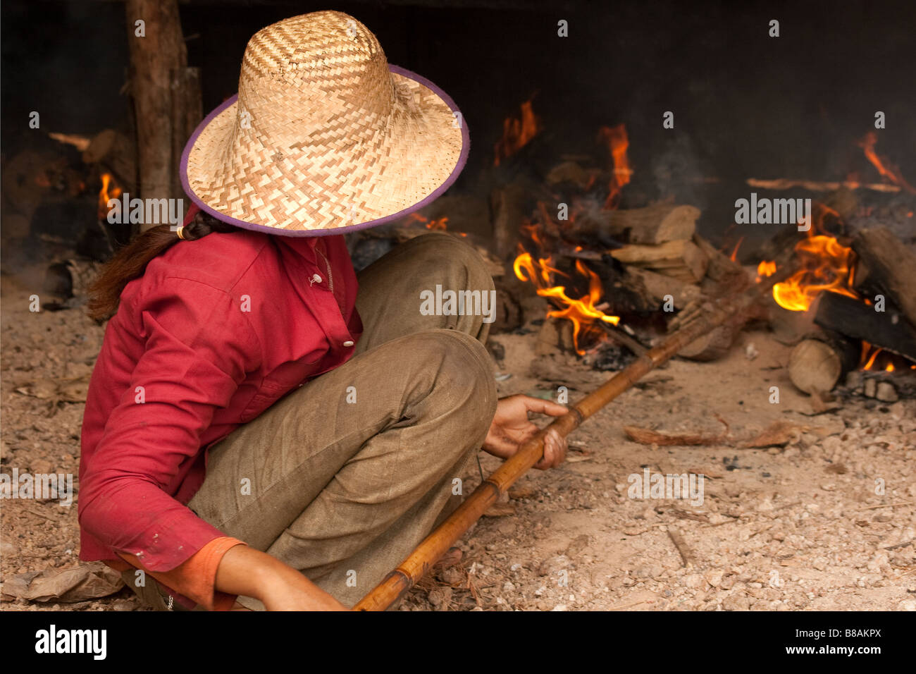 Kambodschanische Mädchen schürt das Feuer, die die Fische, die mit traditionellen Methoden an einem verarmten Dorf am Fluss Mekong (Kambodscha) Rauchen Stockfoto