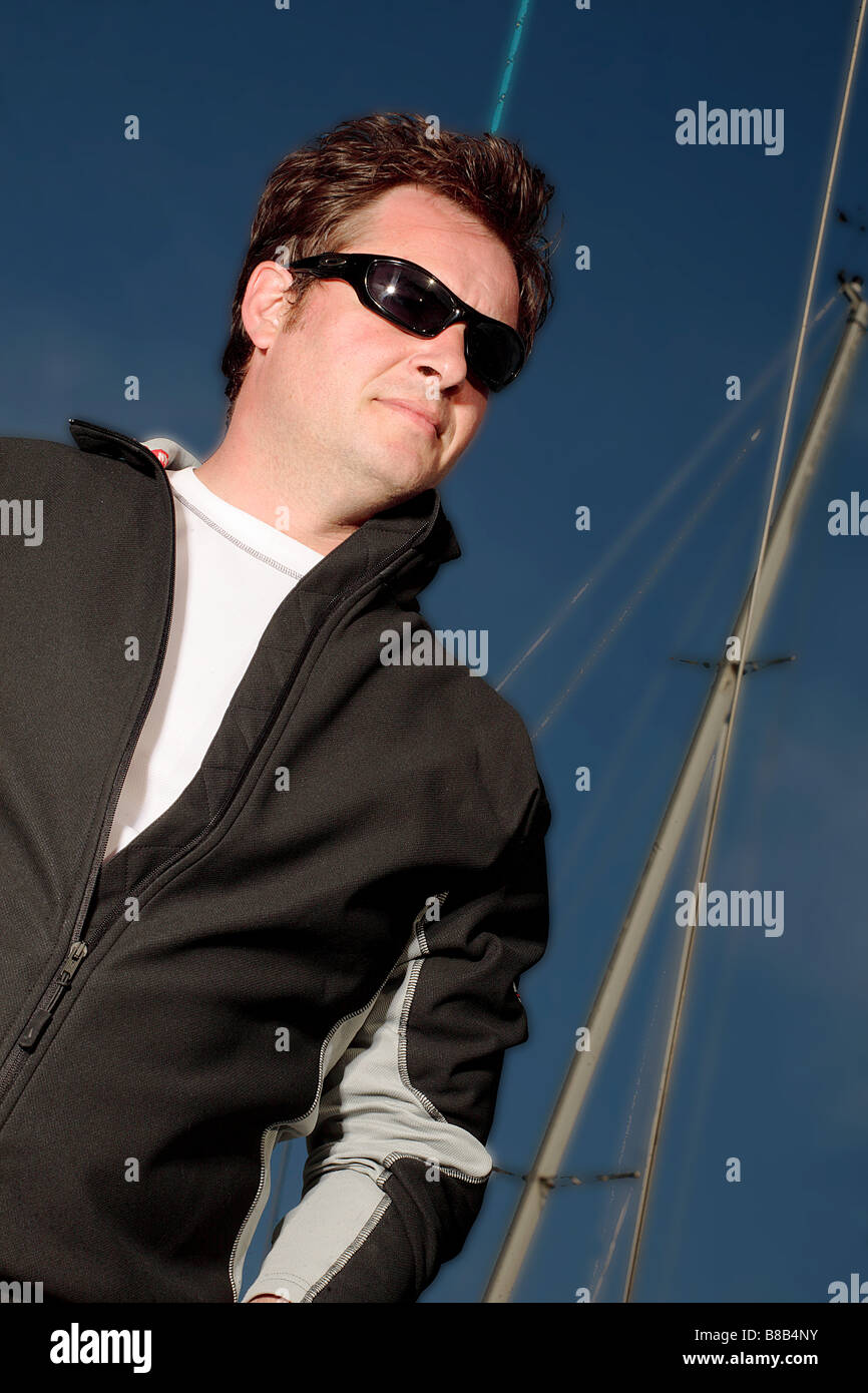 Männlich Alter 30 eine Segelyacht, ist das Bild eine Farbe Portrait zeigt das Modell im Profil mit den Masten der Schiffe im Hintergrund. Stockfoto