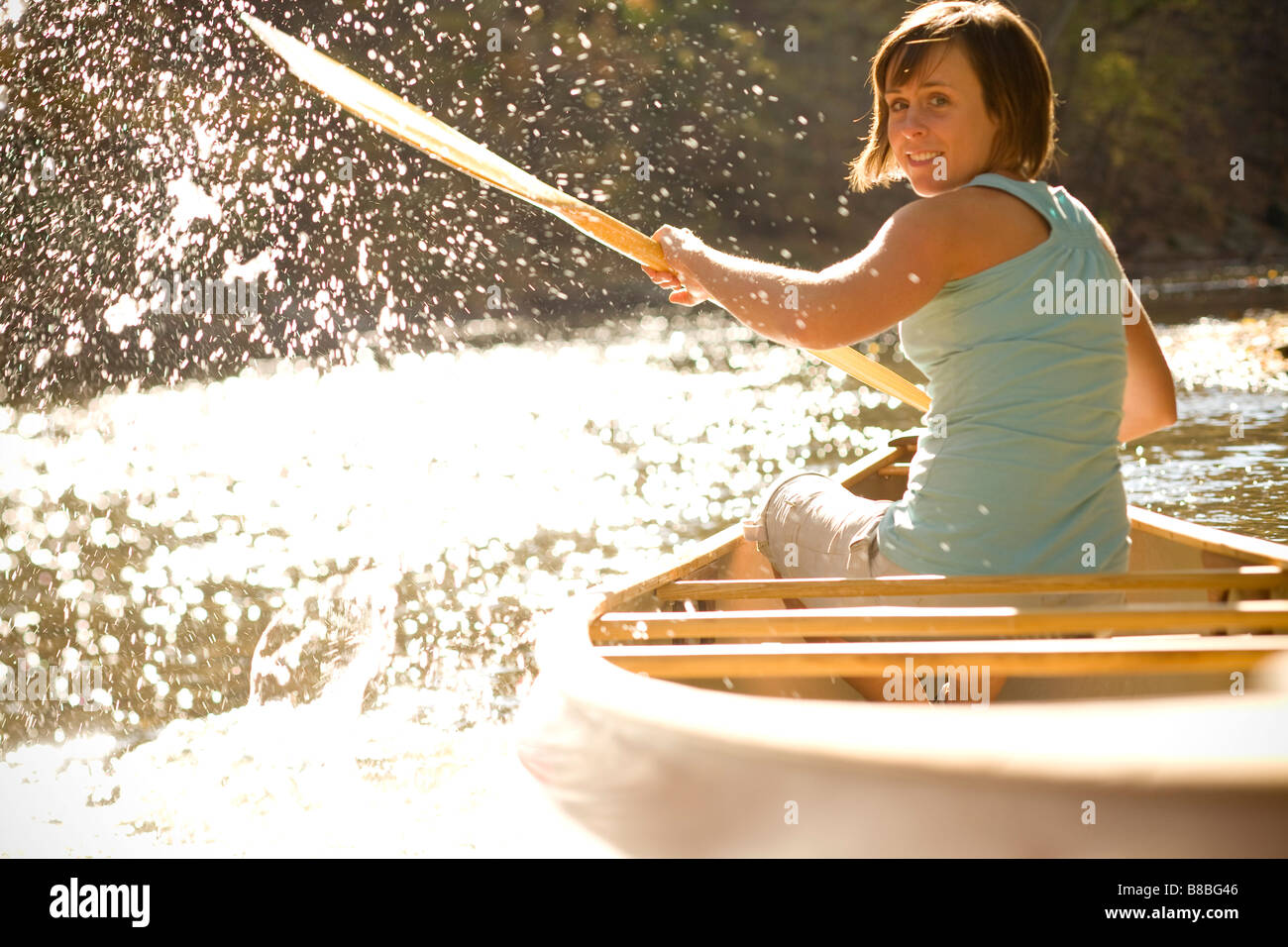 Frau spritzt Wasser hinter Kanu im Fluss Stockfoto