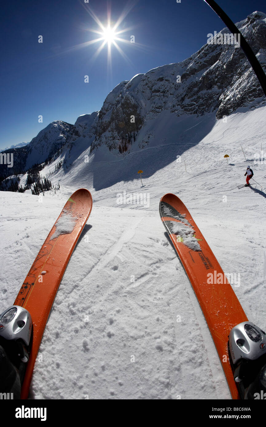 Blick sonnige Ski-Hügel durch die Beine des Fahrers Stockfoto