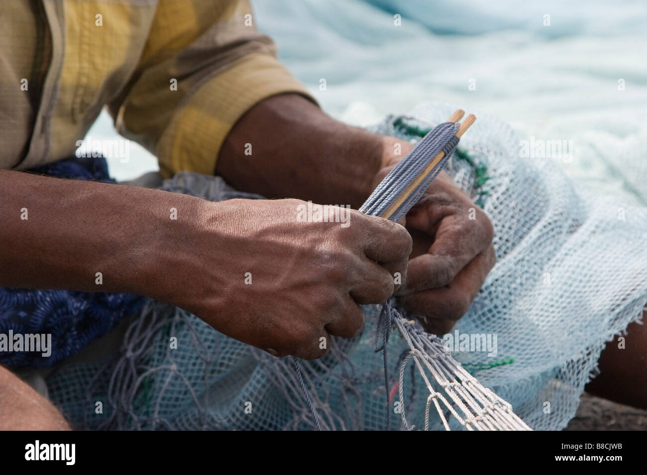 Fujairah, Vereinigte Arabische Emirate, A Fischer behebt Löcher und Verwicklungen in seinem Netz in Fujairah. Stockfoto