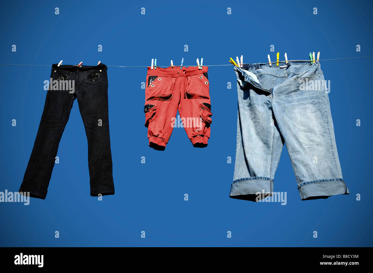 Kleidung auf einer Wäscheleine trocknen in der Sonne vor blauem Himmel. Stockfoto