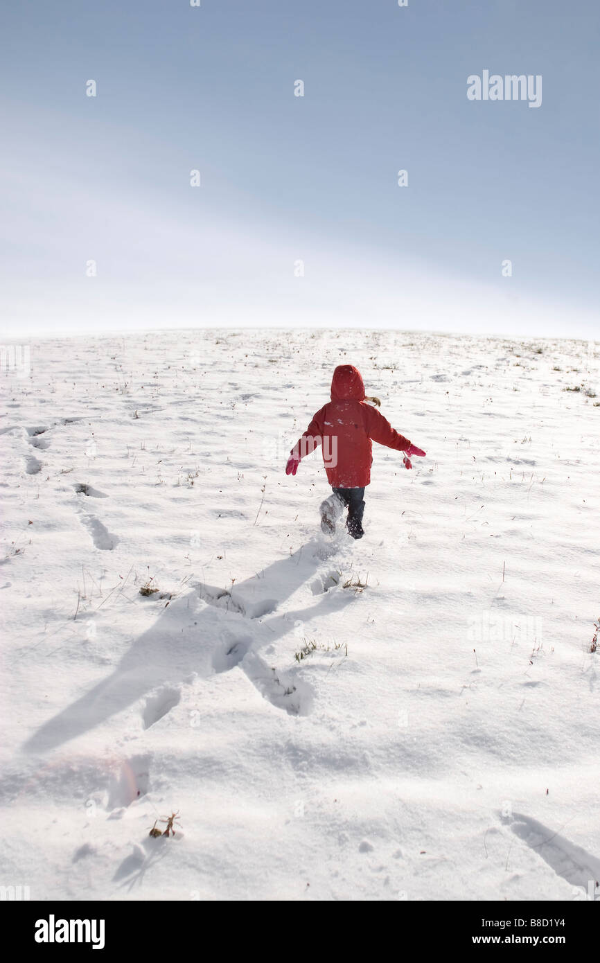 Junge Mädchen laufen durch Schnee bedeckt Feld Stockfoto