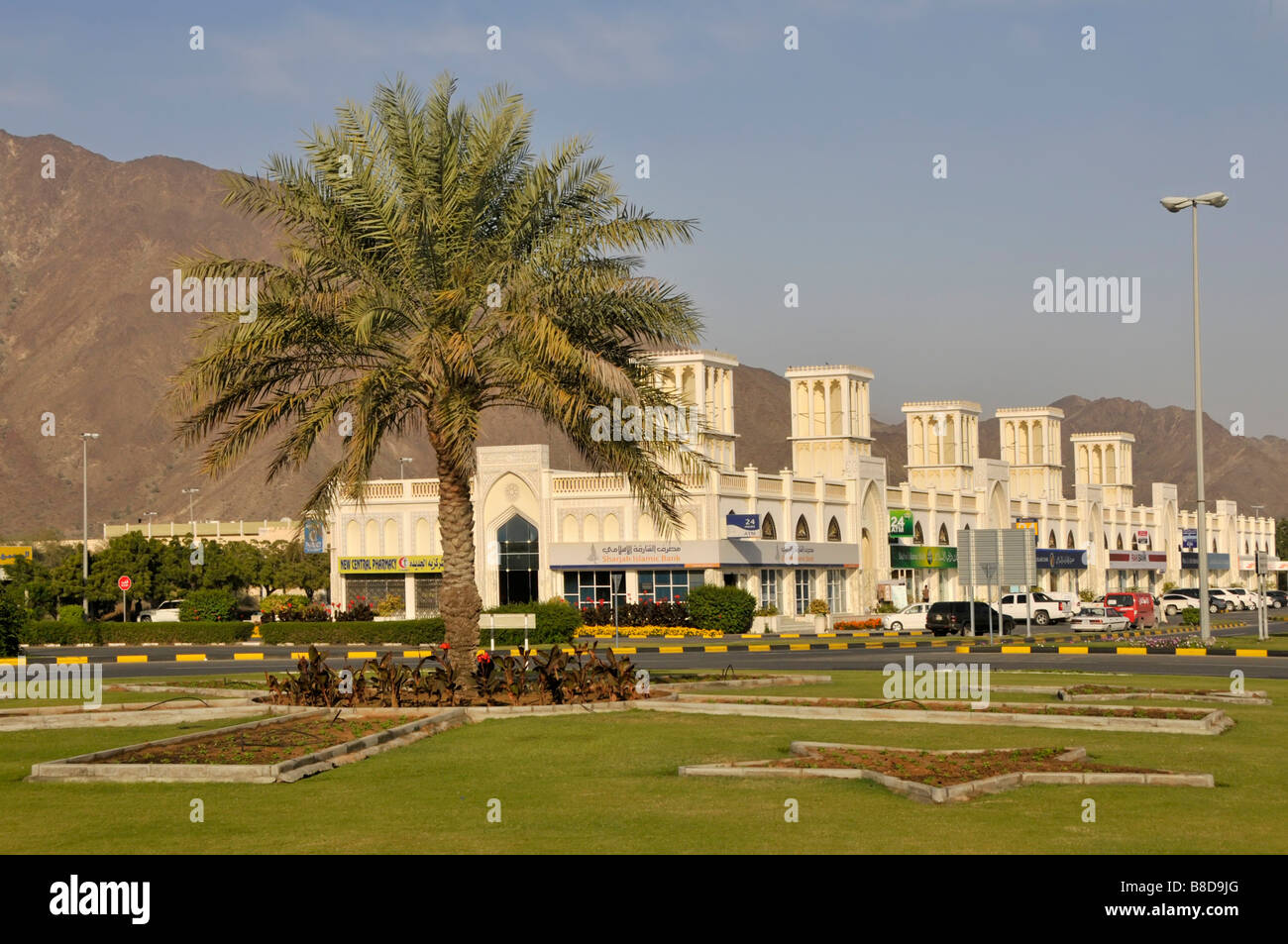 Emirat Sharjah am Golf von Oman eines der Vereinigten Arabischen Emirate, Palme und Reihe von modernen Shop-Einheiten einschließlich der Banken Stockfoto