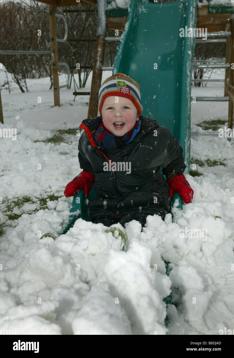 Kinder spielen im Schnee mit einer Folie auf einem Klettergerüst Stockfoto