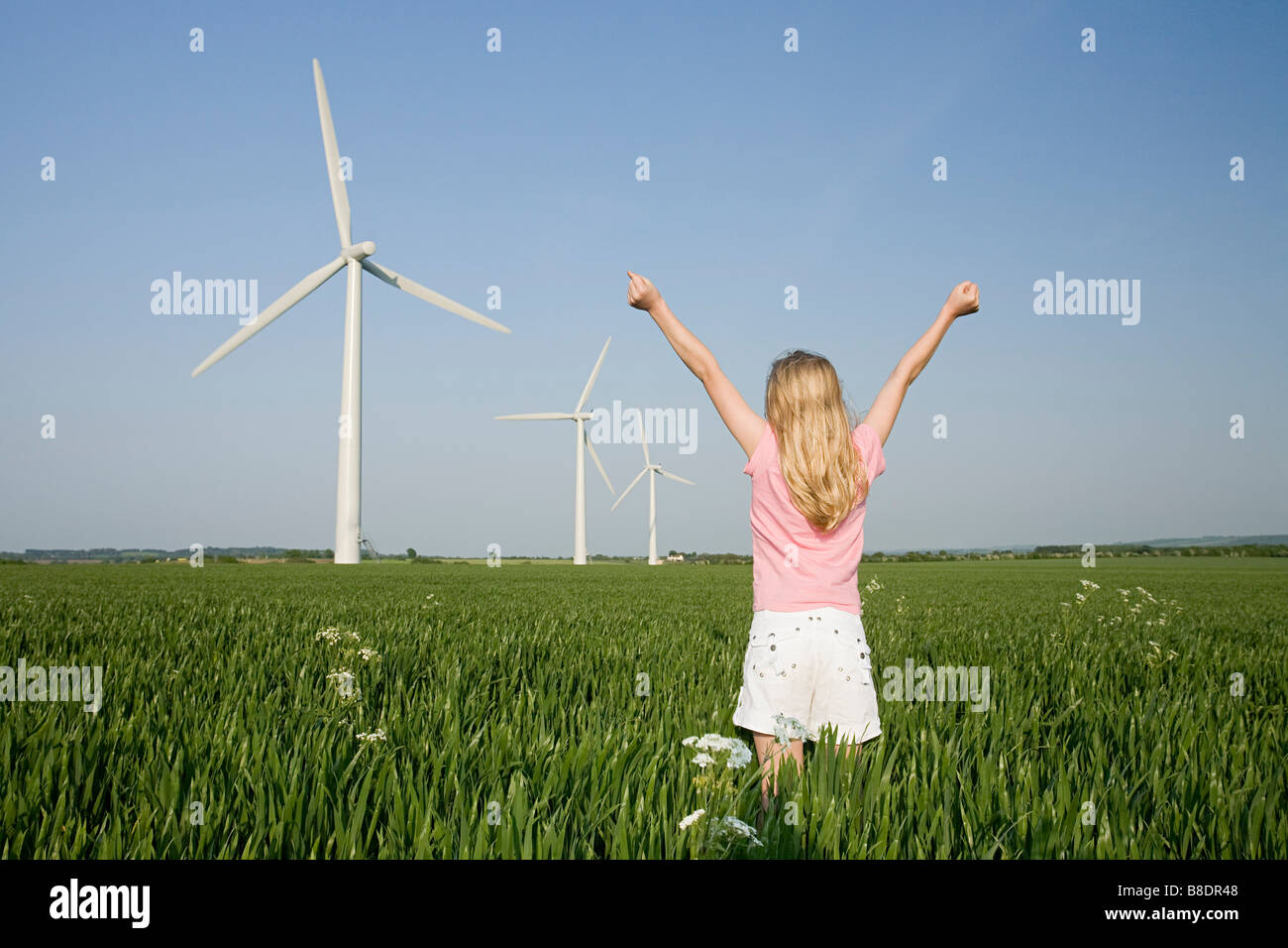 Mädchen in einem Feld von Windparks Stockfoto