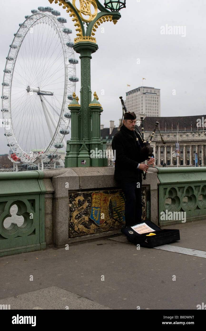 Mann spielt Dudelsack auf Westminster Bridge mit dem London Eye im Hintergrund. Stockfoto
