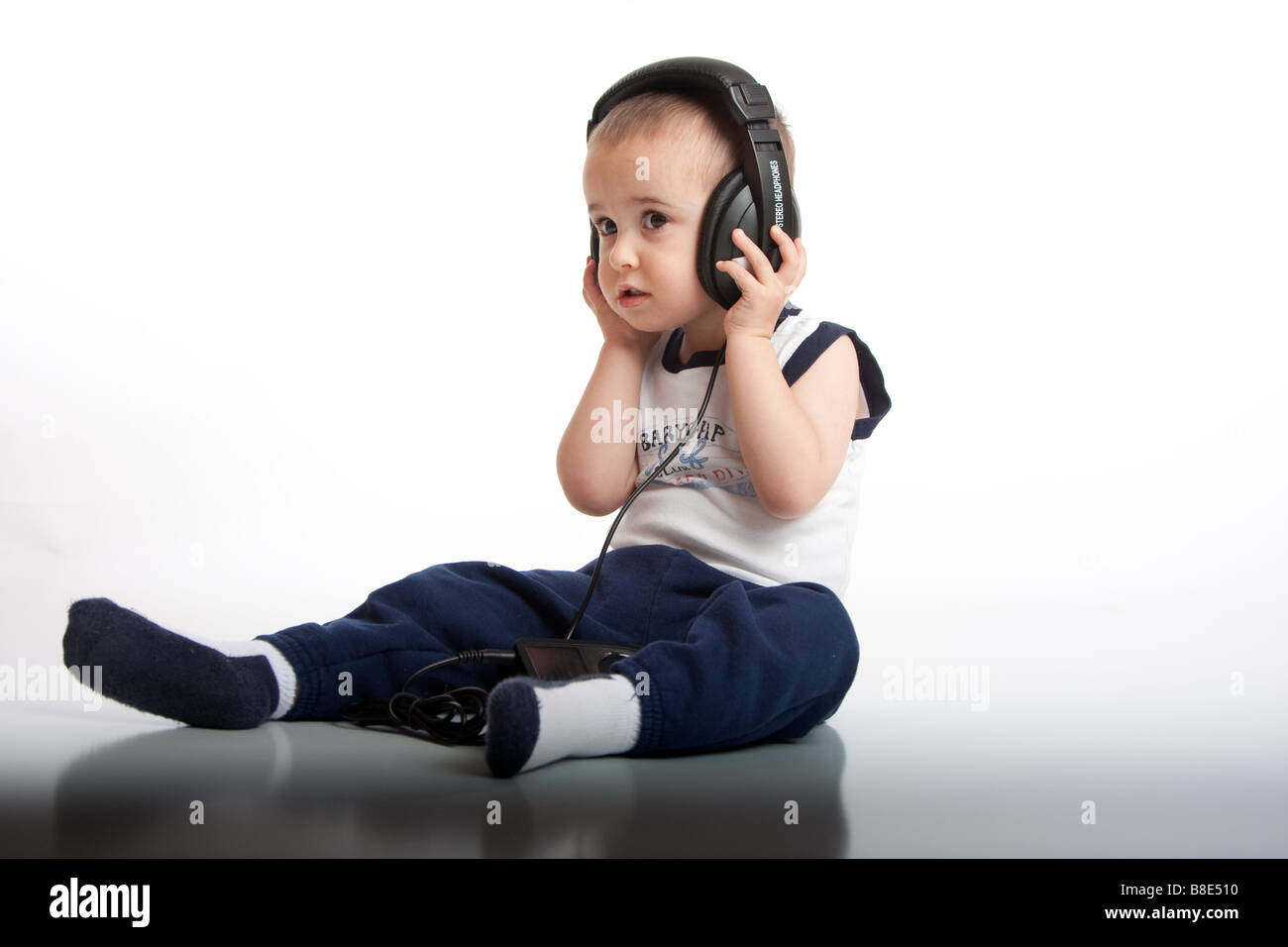 ein 2 Jahre alter Junge hört ein Apple Ipod auf Stereo-Kopfhörer. Stockfoto