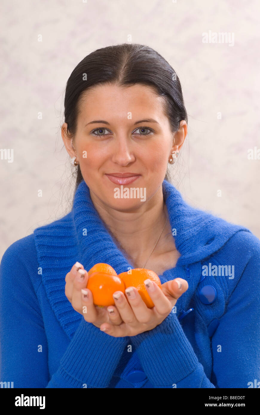 Schöne junge Frau hält eine Mandarine Frucht Stockfoto