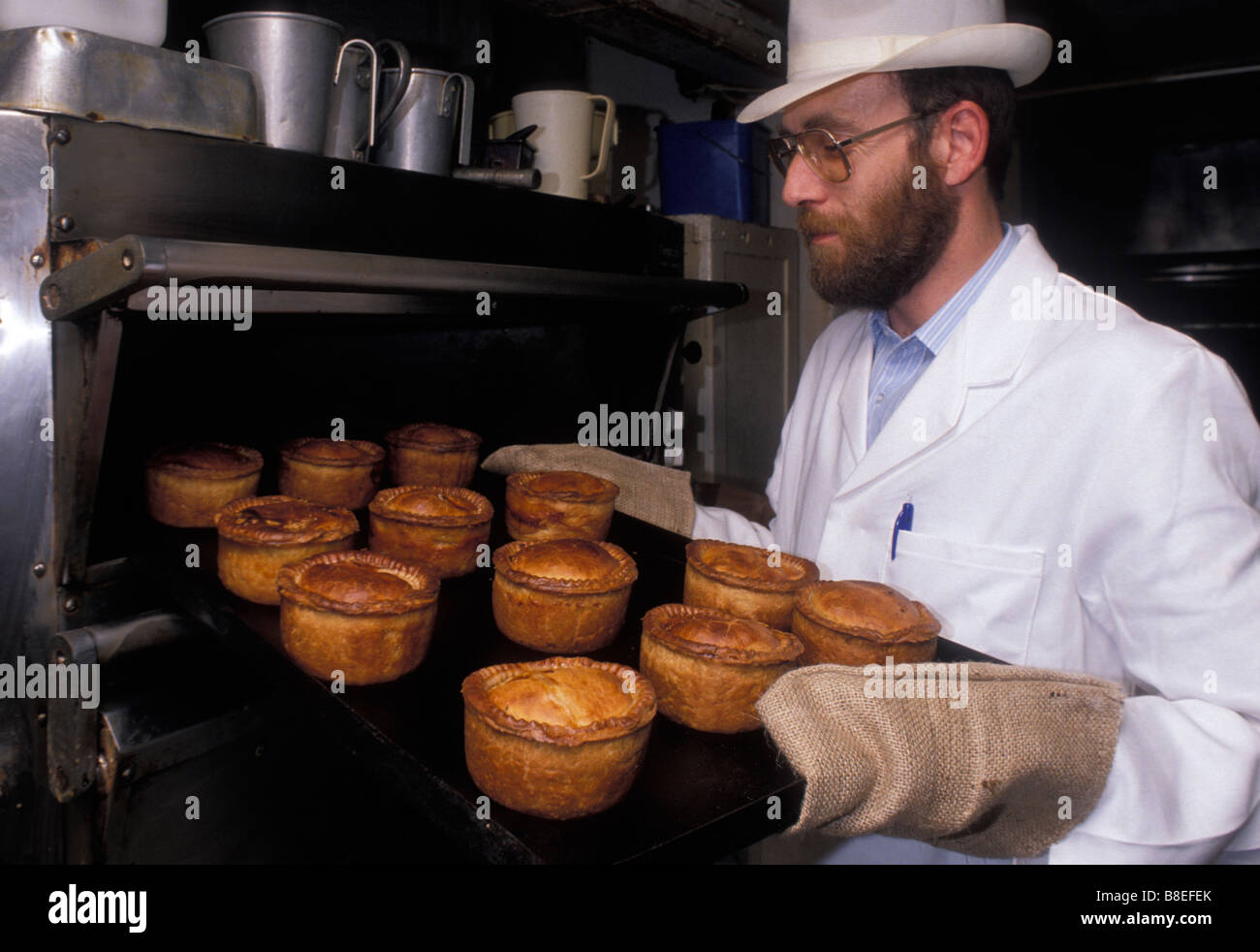Ein Bäcker aus Ye Olde Pork Pie Shoppe in Melton Mowbray hält ein Tablett mit Schweinefleischpasteten frisch aus dem Ofen. Leicestershire. UK Stockfoto
