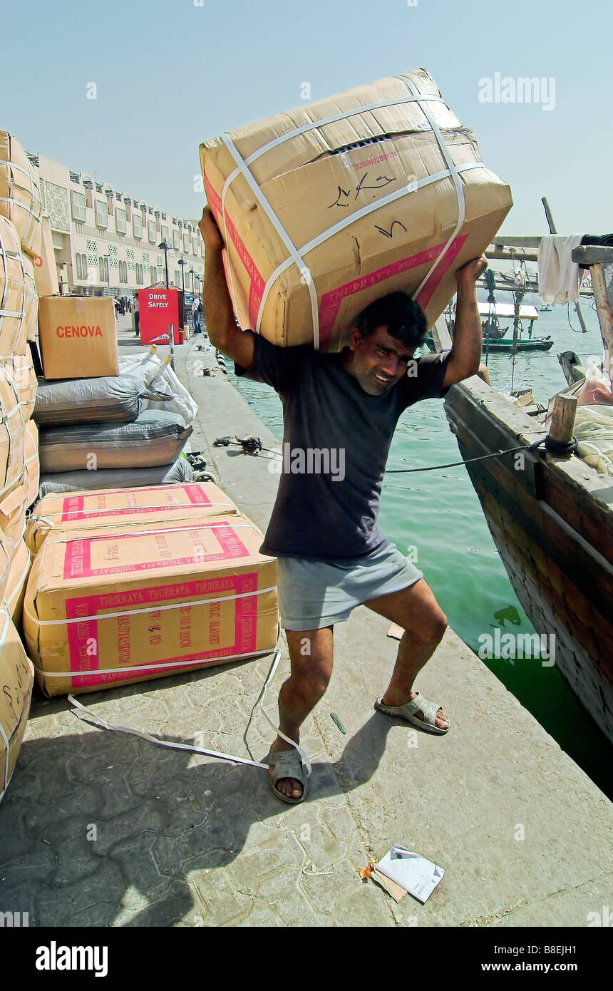 Mann laden Lieferungen auf traditionelle Fracht Boote Dhaus The Creek, Dubai Stockfoto
