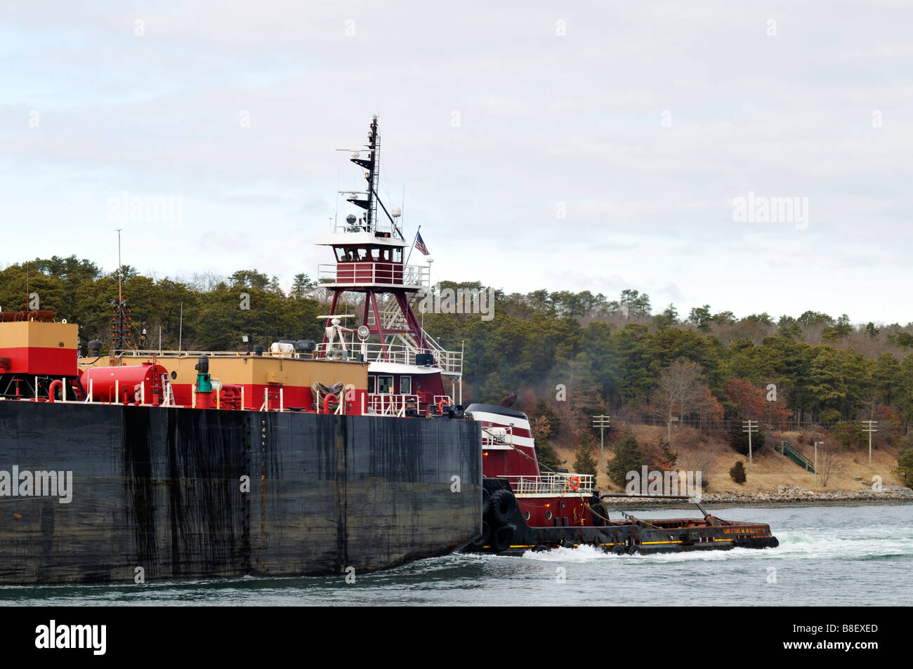 Schlepper drängen Heizöl Lastkahn vorbei Küstenlinie an bewölkten Tag Cape Cod Massachusetts, USA Stockfoto