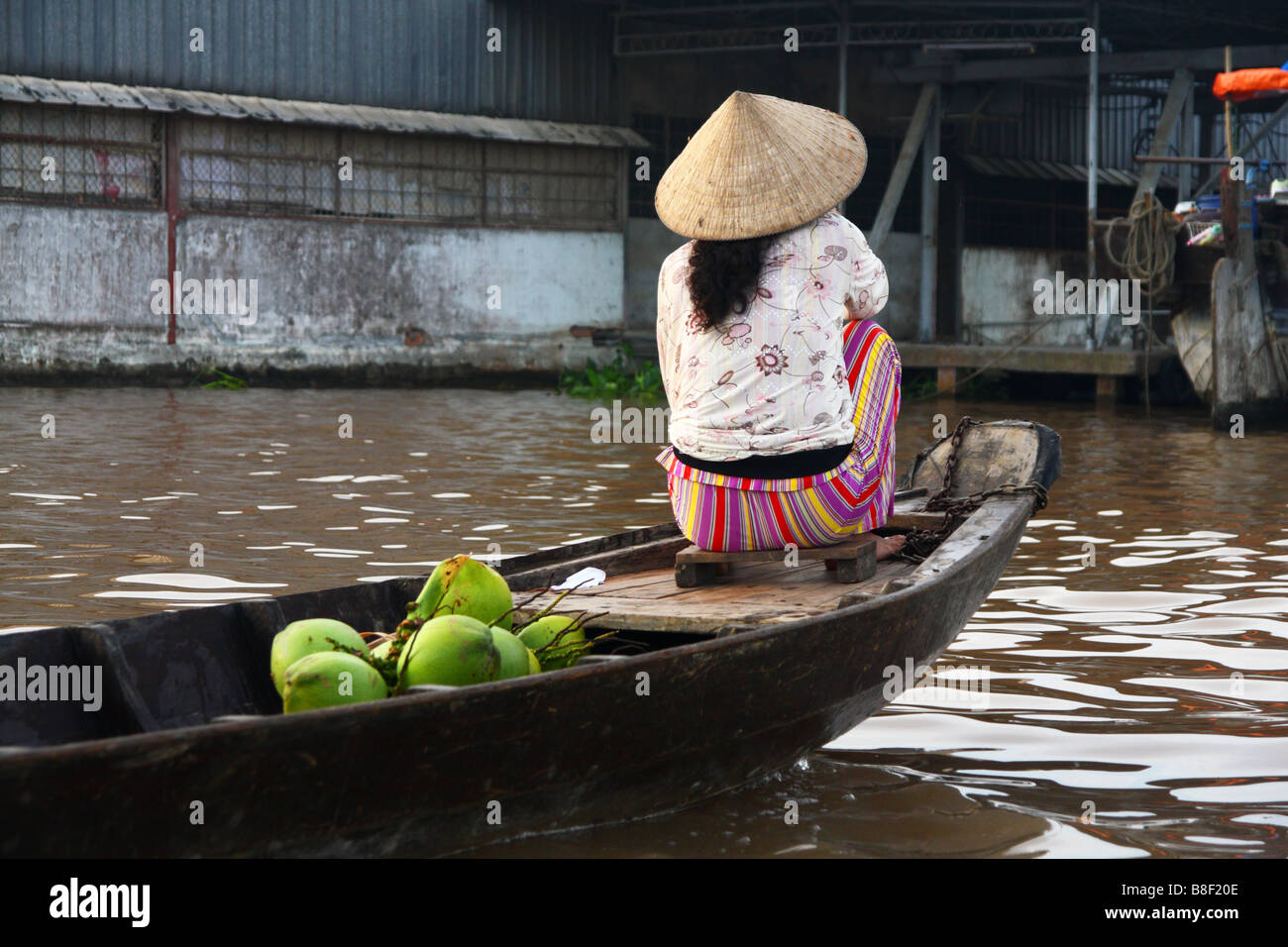 Frau mit einem traditionellen konischen Hut auf ihrem Boot mit einigen Kokosnuss auf dem Mekong in Can Tho schwimmenden Markt. Vietnam Stockfoto