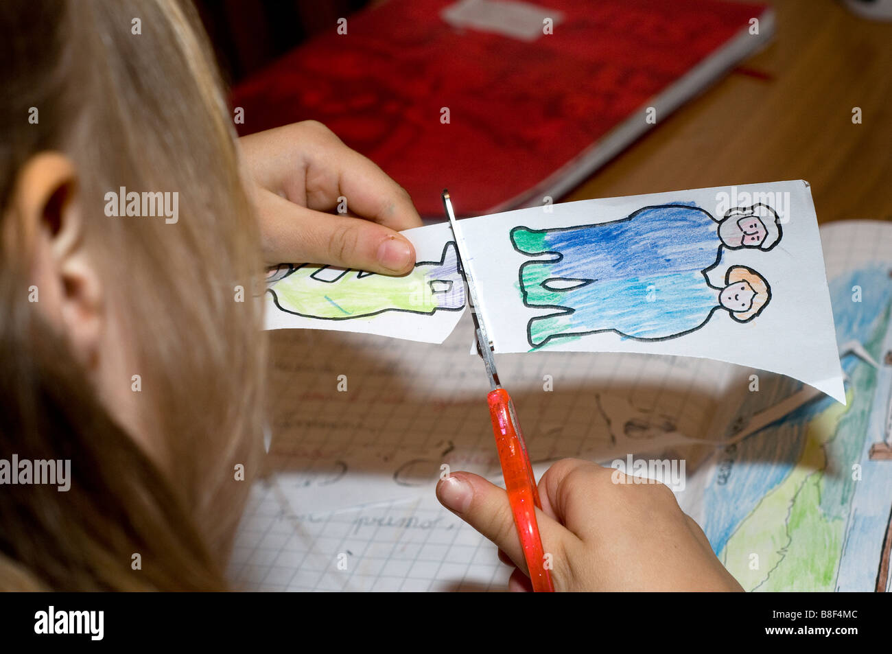 Ein junges Mädchen ist damit beschäftigt, Papierfiguren auszuschneiden Stockfoto
