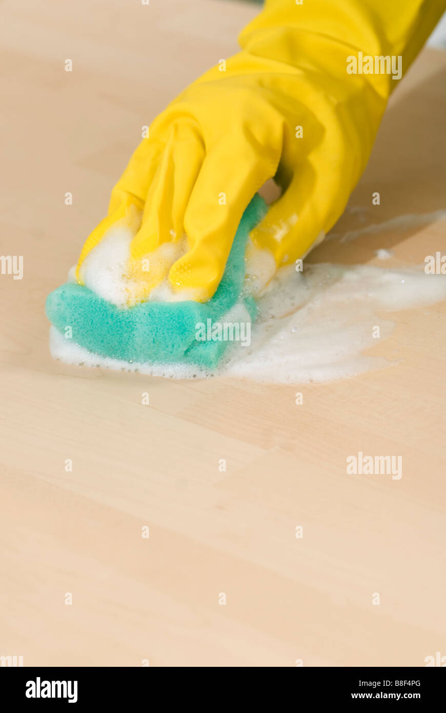 Nahaufnahme von Frauenhand in gelbe Gummihandschuhe, eine Oberfläche mit einem Schwamm schrubben Stockfoto
