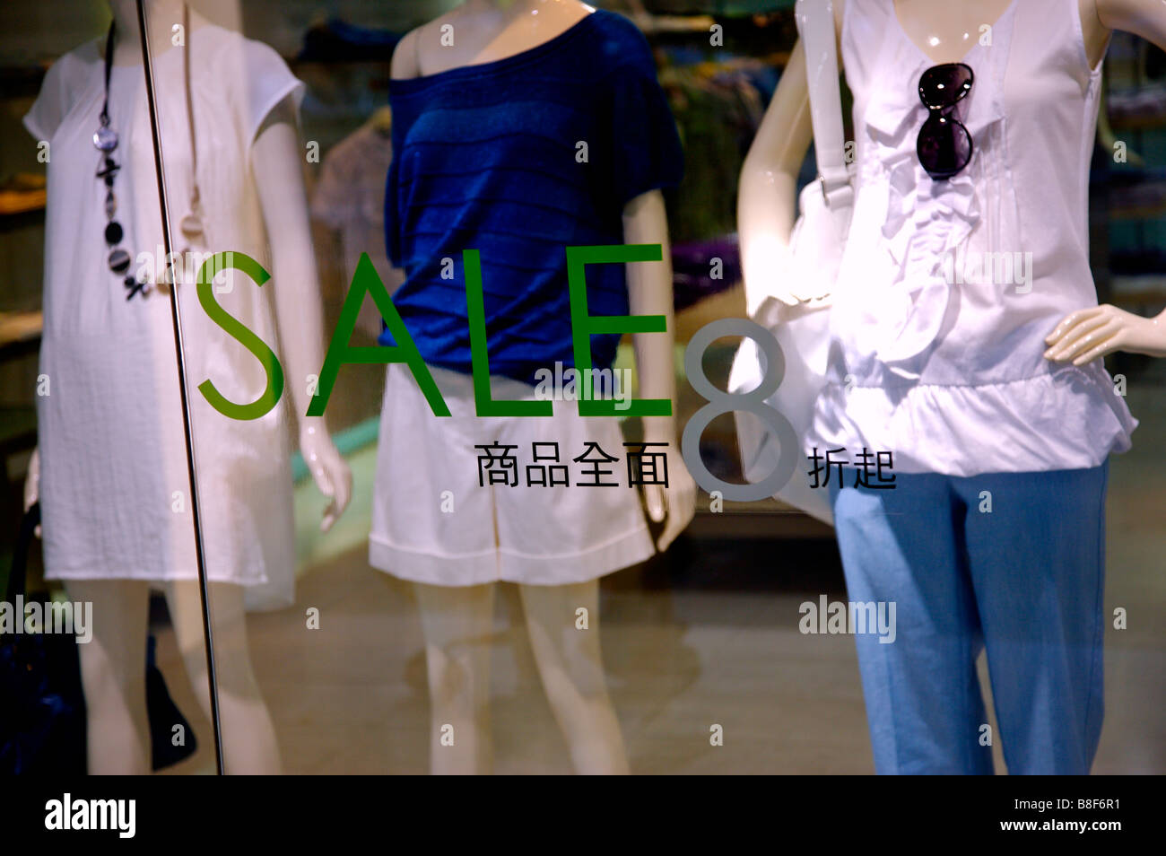 Am Verkaufsschild im Fenster ein Bekleidungsgeschäft vor der drei weibliche Schaufensterpuppen Stockfoto
