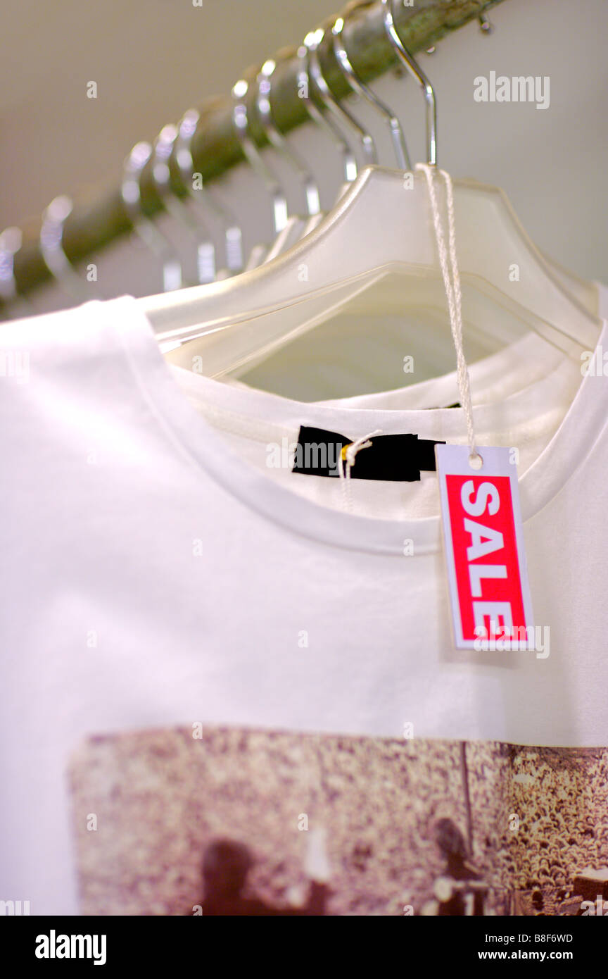 Rote und weiße Verkaufsschild auf einem Kleiderbügel vor ein weißes T-Shirt mit Muster Stockfoto