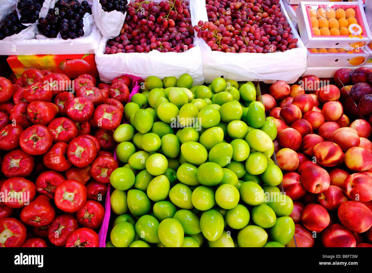 Frisches Obst, darunter grüne Termine wachsen Äpfel Pfirsiche Mispeln und Trauben auf dem Display in Boxen an einem Marktstand Stockfoto