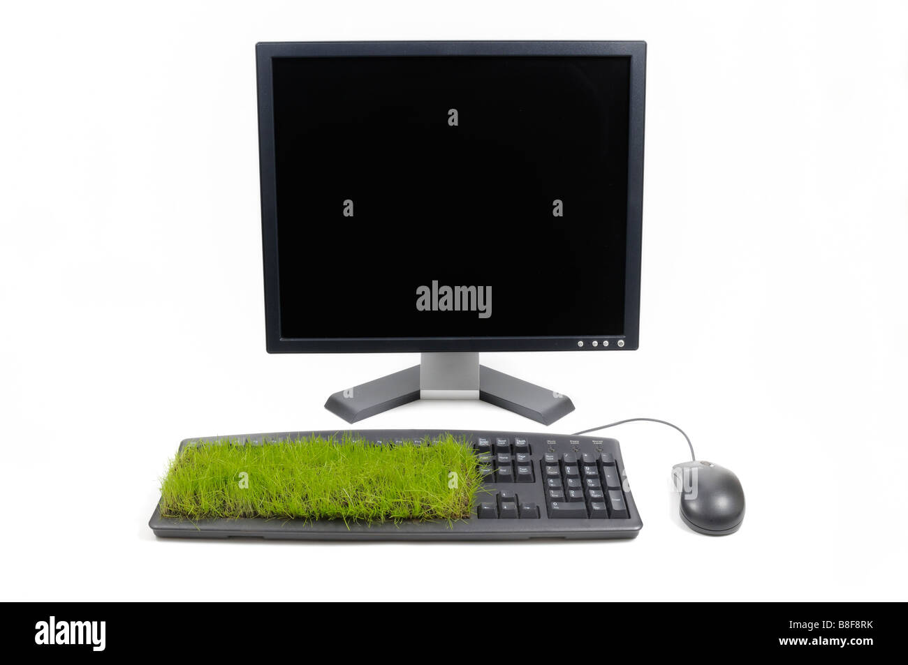 Desktop-Computer, Maus und Tastatur mit Grass wachsen aus ihm heraus. Stockfoto