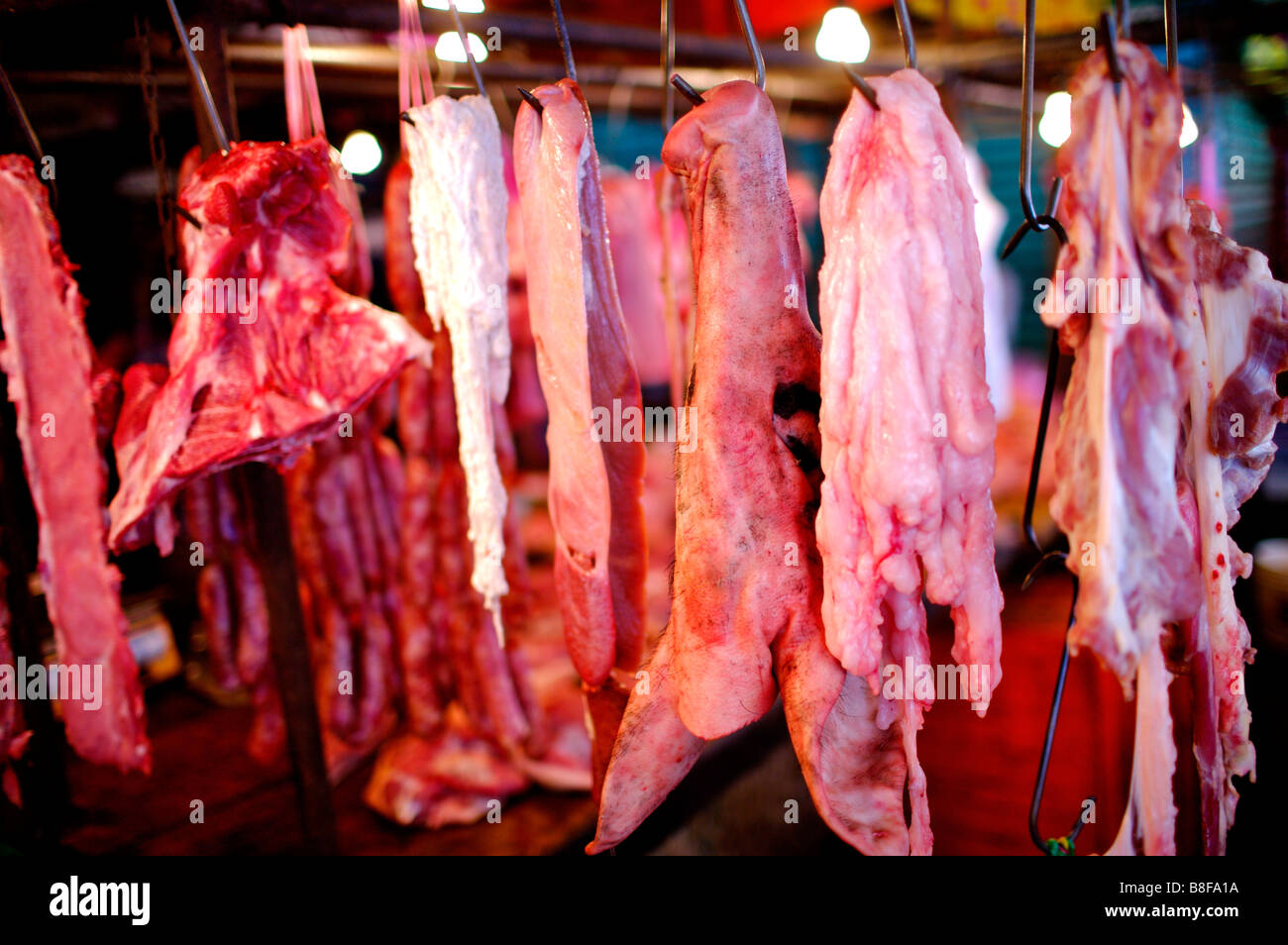 Stücke von rohem Schweinefleisch von Metall-Haken an einem Marktstand hängen Stockfoto