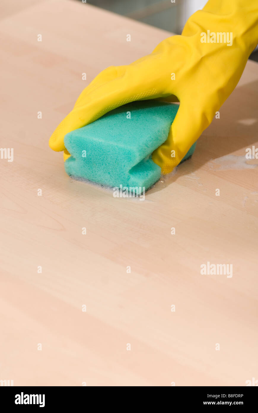 Nahaufnahme von Frauenhand in gelbe Gummihandschuhe, eine Oberfläche mit einem Schwamm schrubben Stockfoto