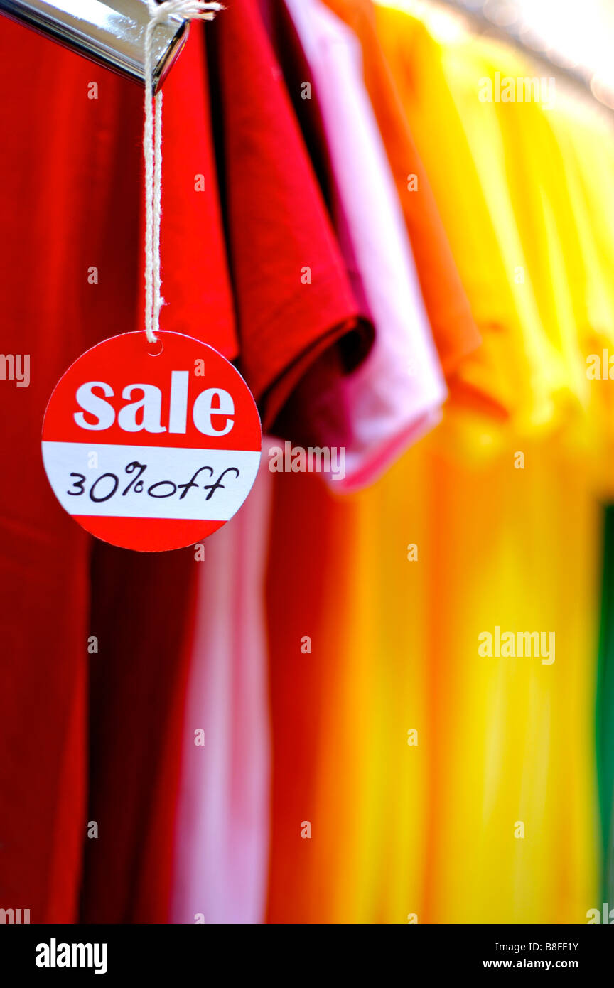 Rote und weiße Rabatt Schild hängen vom ein-T-Shirt vor einer Reihe von bunten t-Shirts Stockfoto