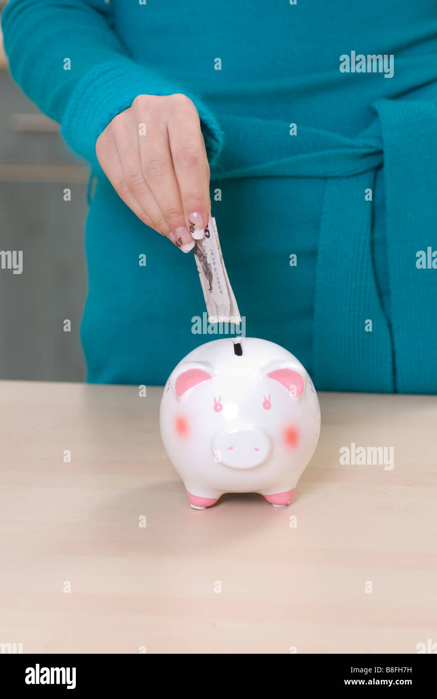 Nahaufnahme einer Frau Geld zu sparen in ein Sparschwein Stockfoto