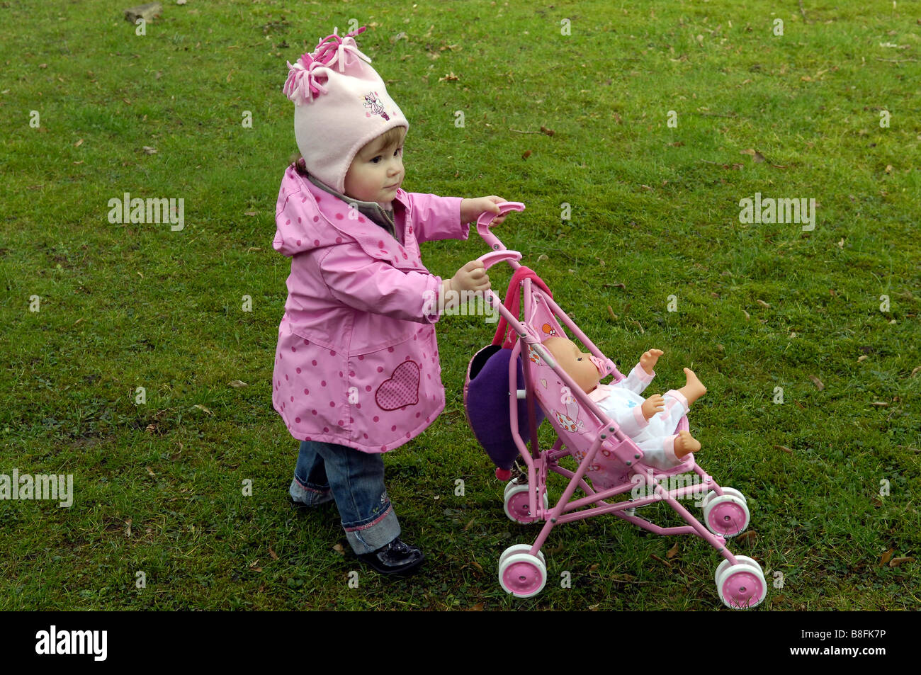 Kleinkind Mädchen Spielzeug Kinderwagen außerhalb Dolly einschieben Stockfoto