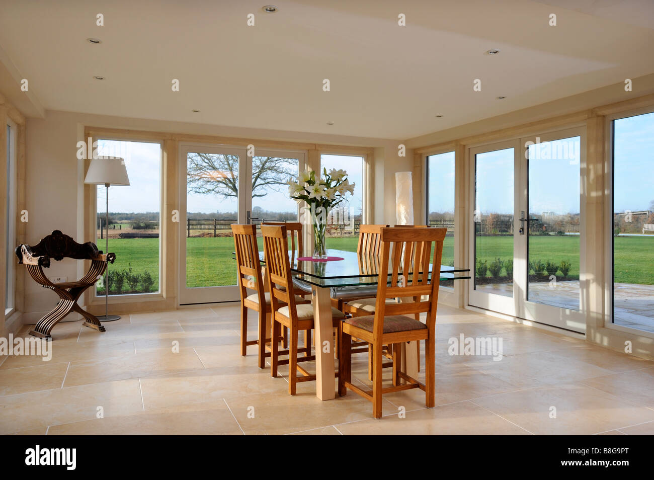 EIN ESSZIMMER UMGEBEN VON TERRASSENTÜREN IN EIN MODERNES LANDHAUS-UK Stockfoto