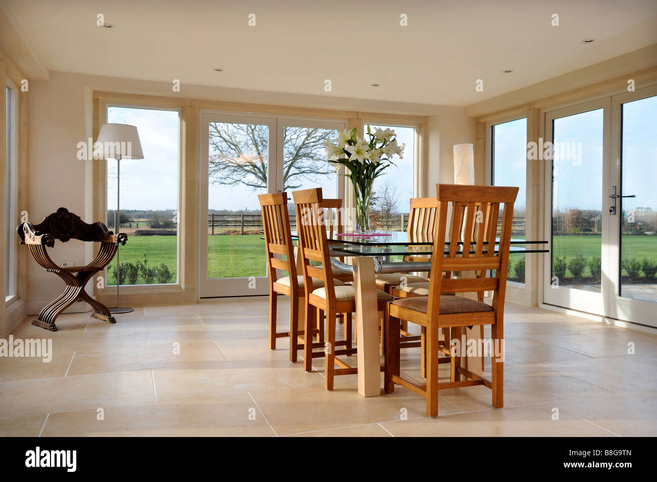 EIN ESSZIMMER UMGEBEN VON TERRASSENTÜREN IN EIN MODERNES LANDHAUS-UK Stockfoto