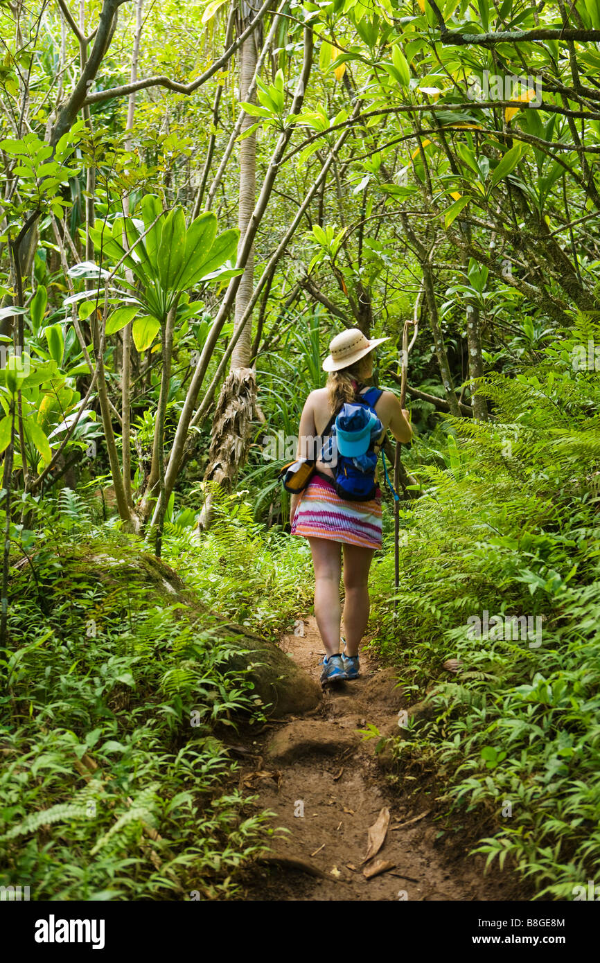 Frau zu Fuß mit einem Wanderstab durch einen tropischen Wald auf der Na Pali Küste von Kauai Hawaii Stockfoto