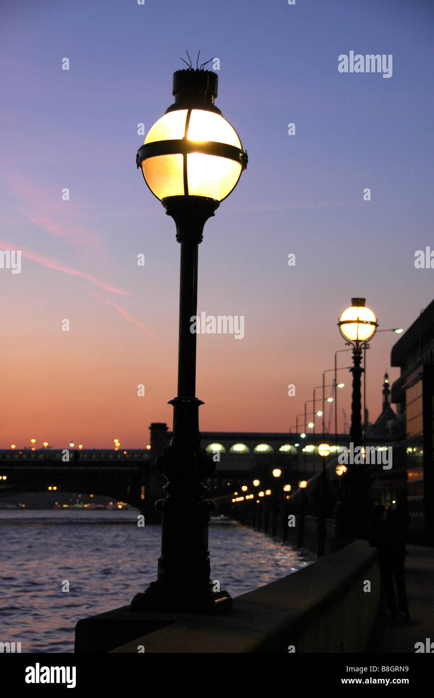 Eine reich verzierte Lampe vor einem Sonnenuntergang Himmel am Victoria Embankment mit Blackfriars Bridge im Hintergrund, London, England, UK Stockfoto