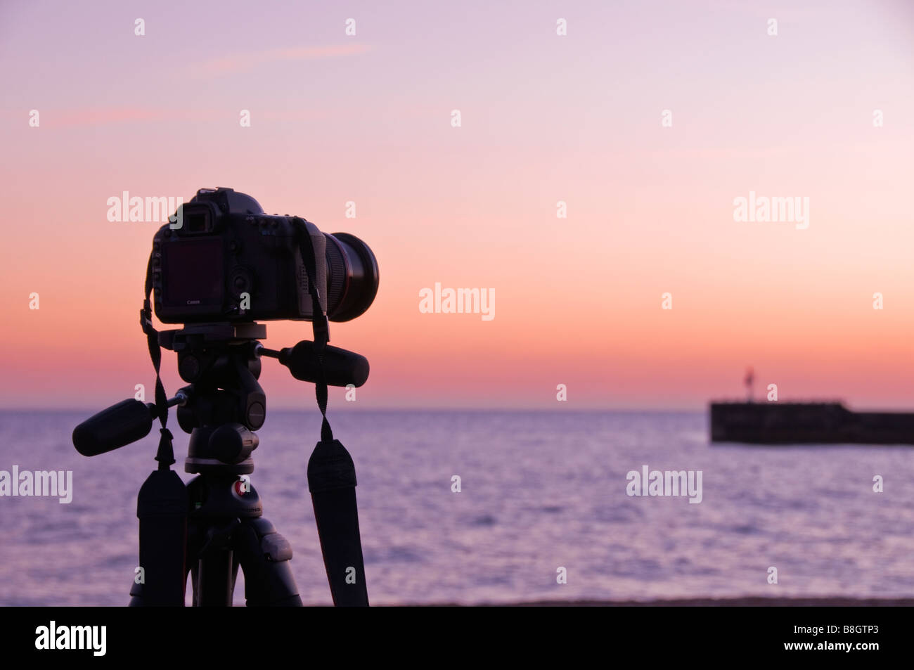 Eine Silhouette einer Kamera montiert auf einem Stativ vor einem Sonnenuntergang Himmel, Hastings, East Sussex, England, UK Stockfoto