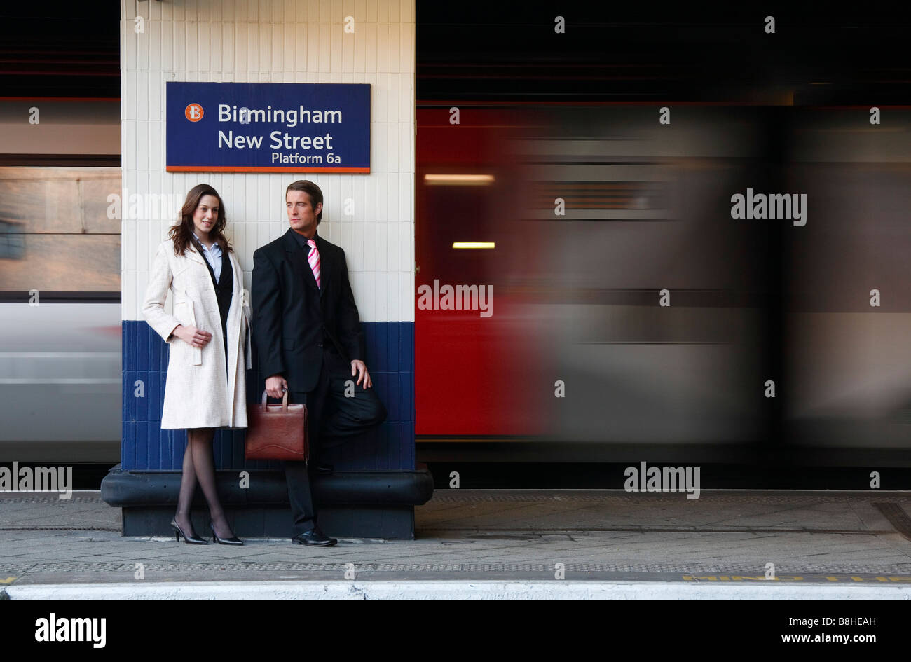 Geschäftsmann und Frau auf eine Bahn Bahnsteig mit einem Zug vorbei Stockfoto