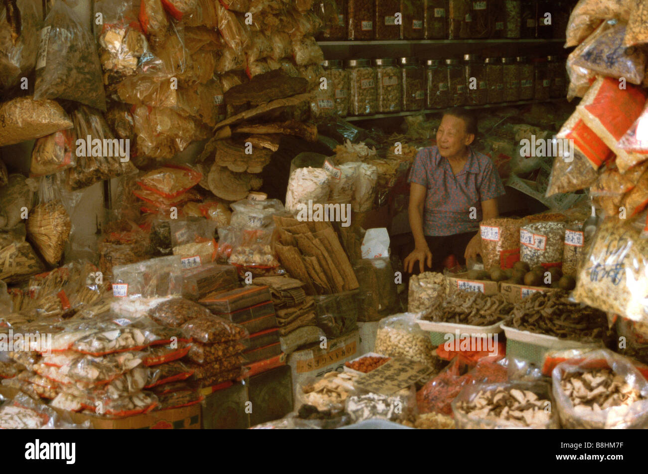 Ältere Verkäufer verkaufen getrocknet, chinesische Heilkräuter und Nahrungsmittel im Großhandel Marktstand Sheung Wan, Hong Kong Insel Stockfoto