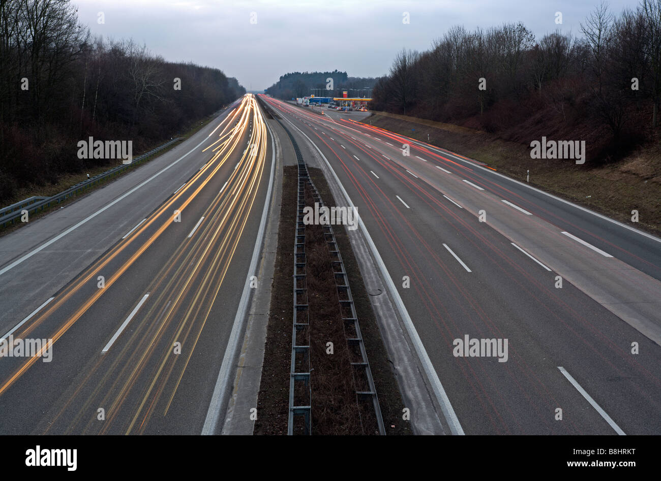 deutsche Autobahn A3 in der Abenddämmerung mit Shell-Tankstelle, Langzeitbelichtung mit hellen Streifen Stockfoto