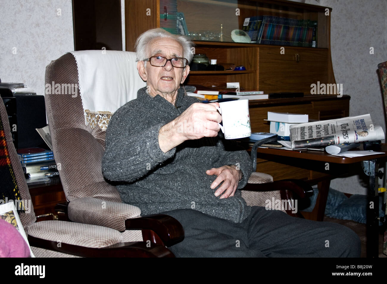 Rentner, die bei einer Tasse Tee in seinem Haus in Schottland Stockfoto