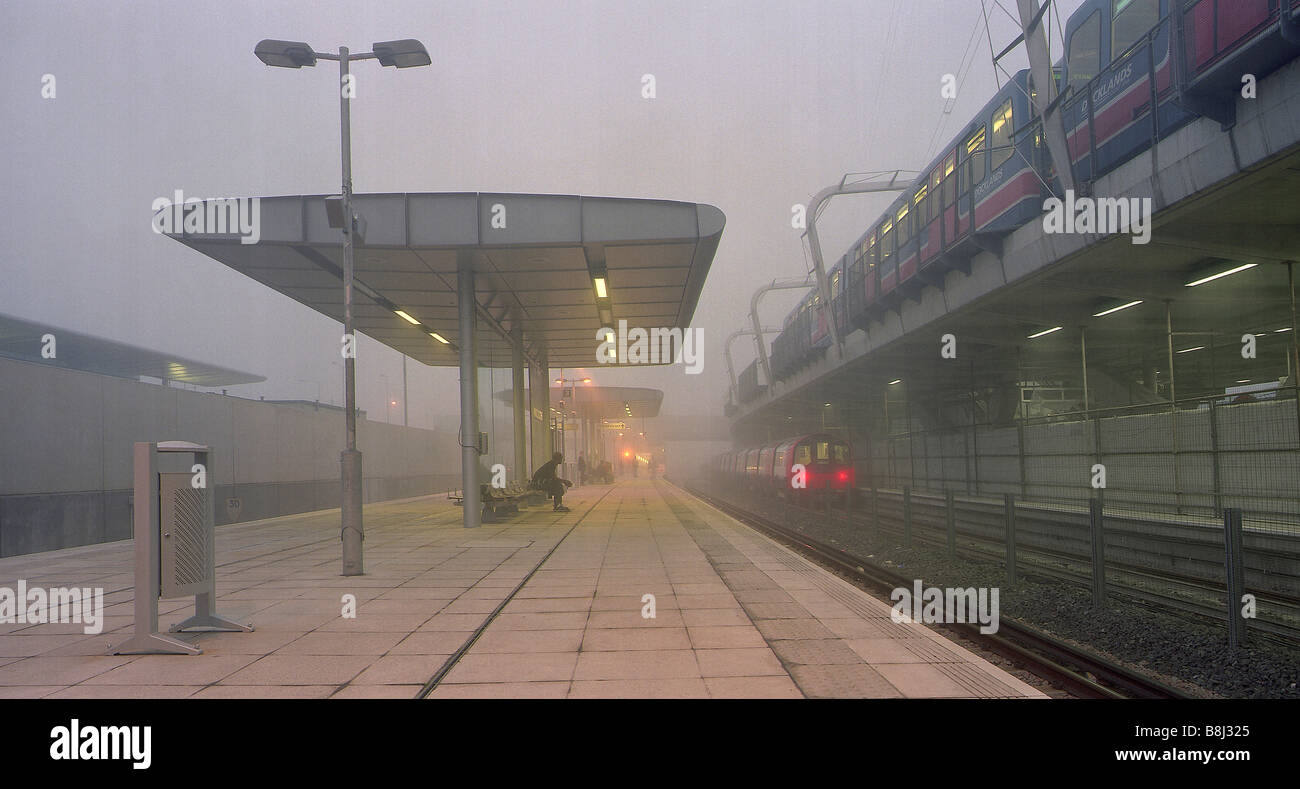 Nebligen vom frühen Morgen an der Jubilee Line Extension Canning Town Station mit Docklands Light Rail Train auf erhöhten Straßenüberführung. Stockfoto