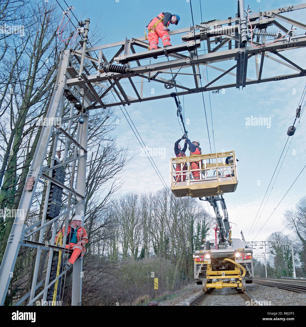 Auftragnehmer auf obenliegende Caternary System hinter teilweise Eisenbahn Blockade, während Züge auf live-Tracks noch ausgeführt werden Stockfoto
