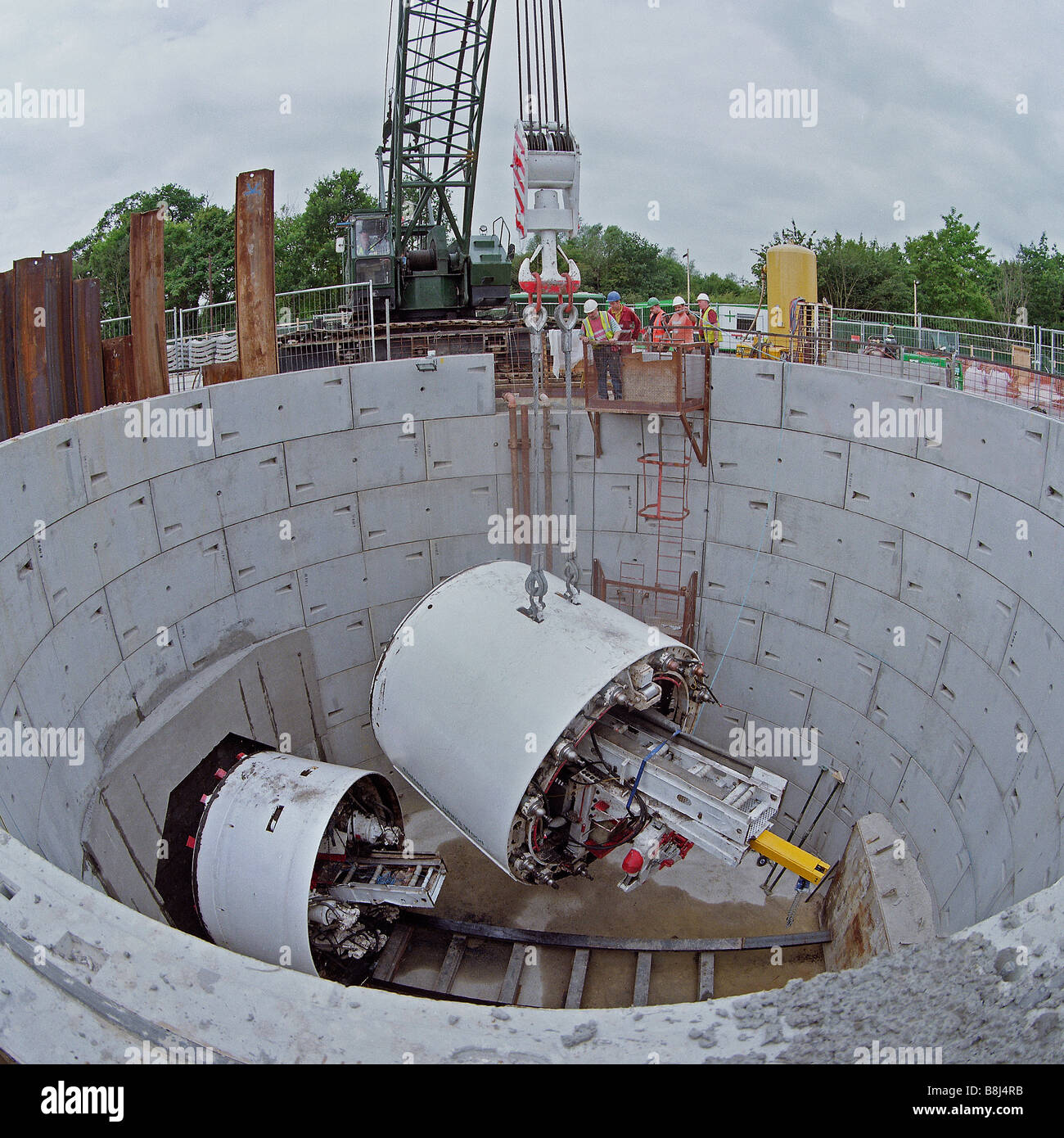 Auftragnehmer, die Senkung der Tunnelbohrmaschine, die Strom Kabel Tunnel in Zugangsschacht in London Graben wird. Stockfoto