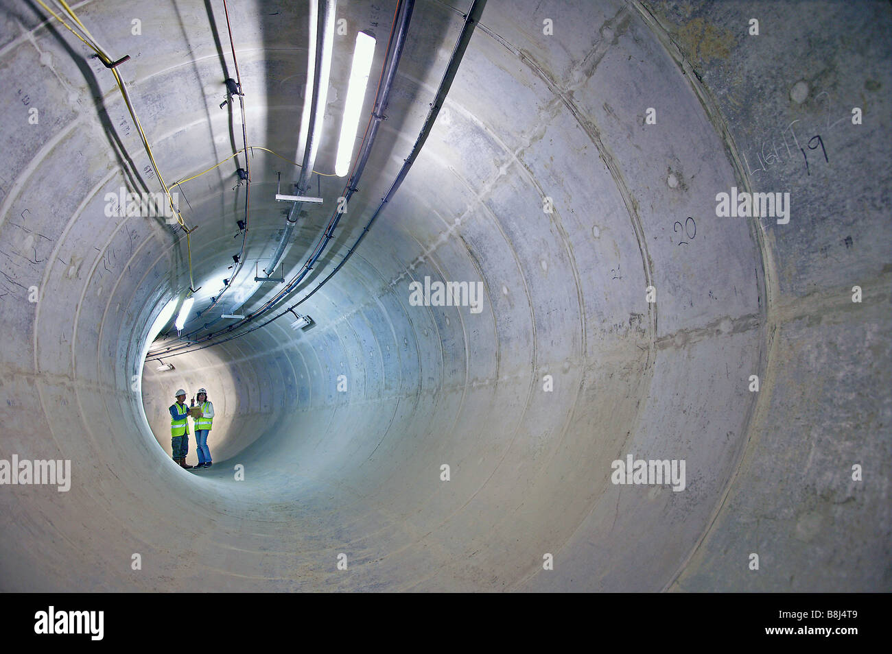 Ingenieure prüfen Zugang Stollen zum Hauptstrom Kabel Tunnel in London, gesäumt von Beton Segmente zu unterstützen. Stockfoto