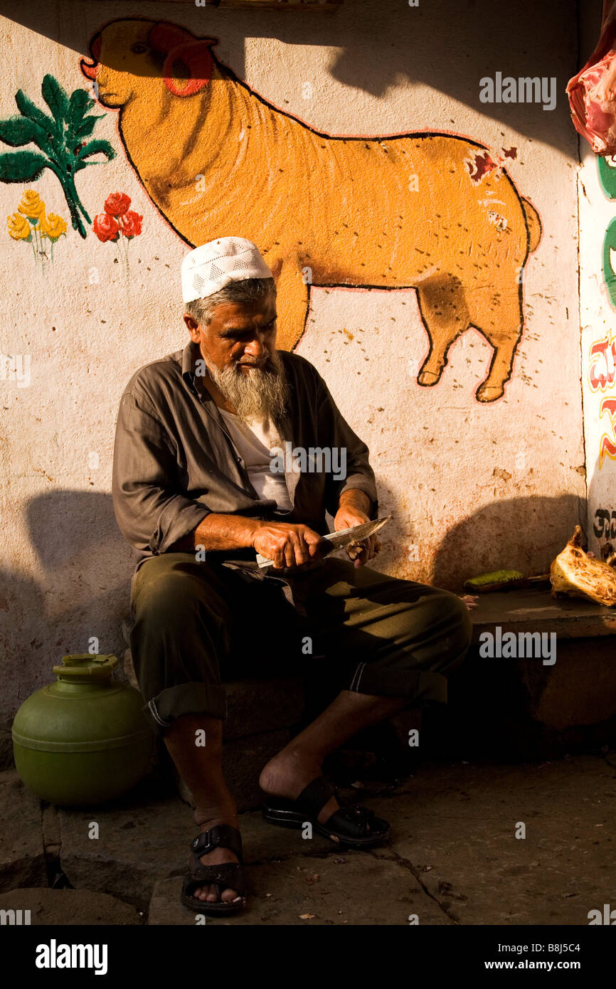 Ein Metzger schneidet Mittelwert aus einer Knochen auf den Streetside in Bangalore, Indien. Stockfoto