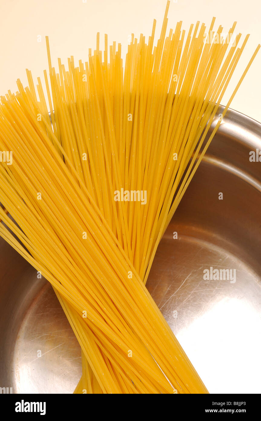 getrocknete Spaghetti in Edelstahl Pfanne ungekocht Rohwasser italienisches Essen Kohlenhydrate Bolognese Küchenutensil kochen weiß bac Stockfoto