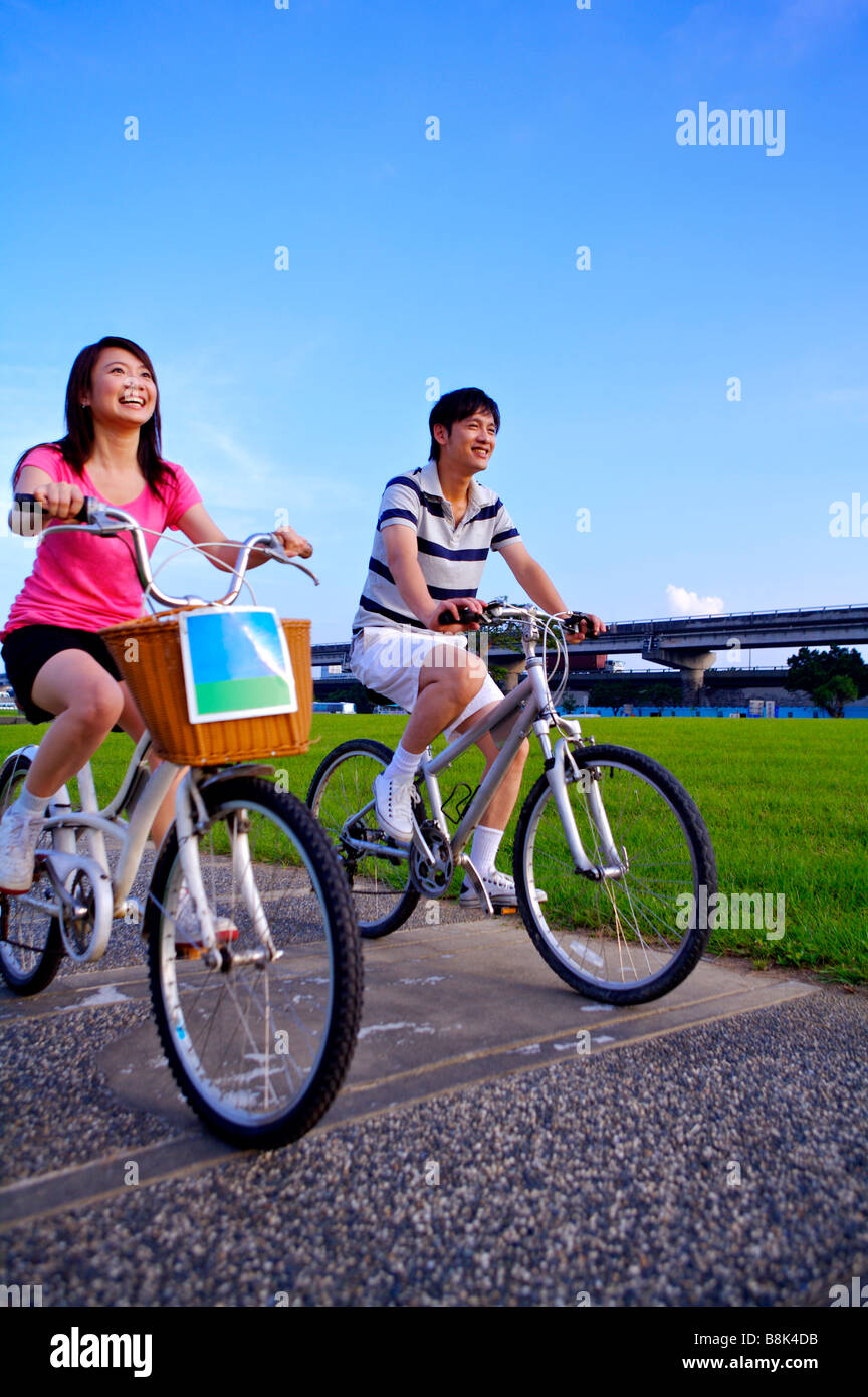 Junges Paar Reiten auf Fahrrädern und wegsehen Flussufer Stockfoto