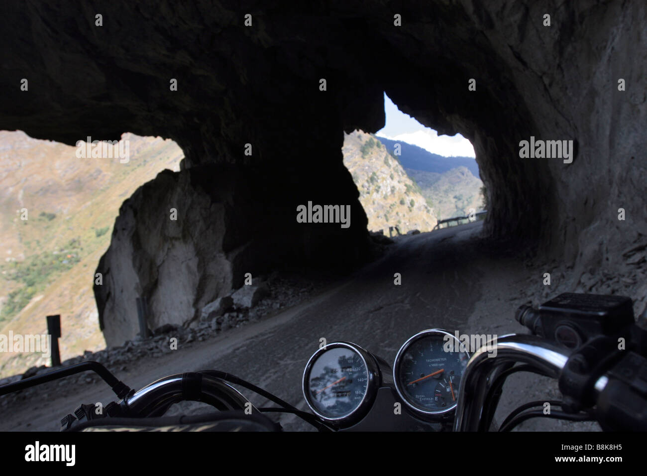 Eine Ansicht von einem Motorrad Sitz einer dramatischen Straße gehauen als Tunnel in den Berghang im indischen Himalaya. Stockfoto