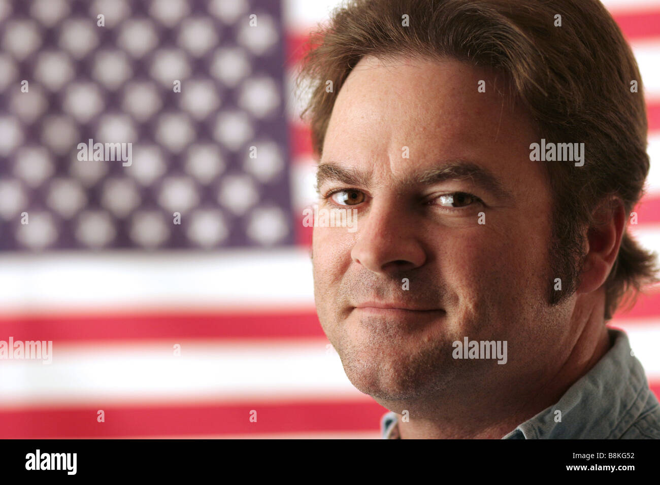 Ein gut aussehender Mann lächelnd vor einer amerikanischen Flagge Stockfoto