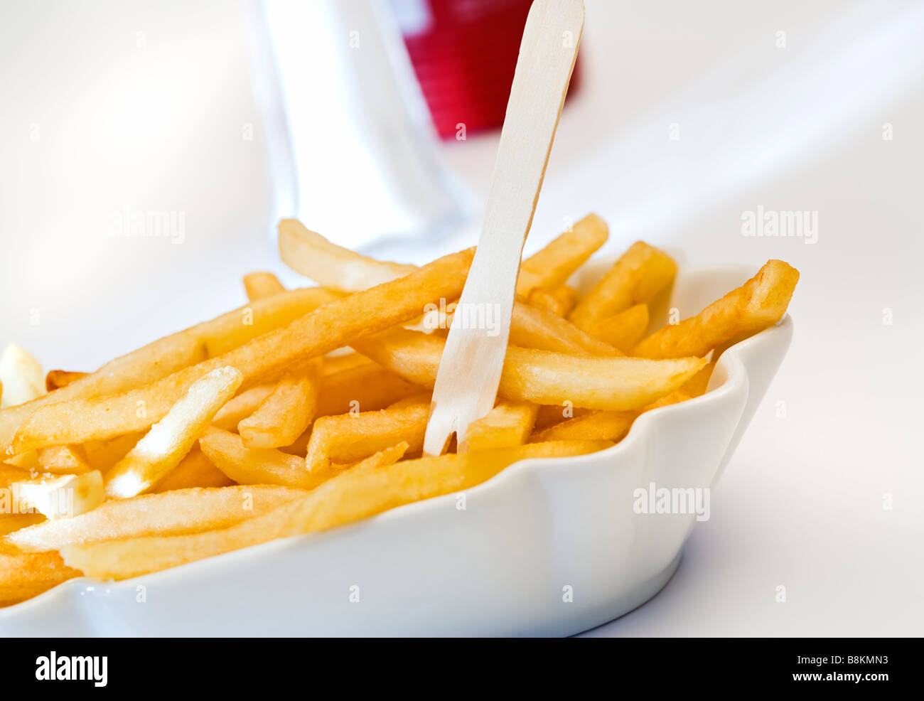 Pommes frites in Keramikschale mit hölzernen Pick, Salzstreuer und Ketchup- Flasche im Hintergrund, schräge Ansicht Stockfotografie - Alamy